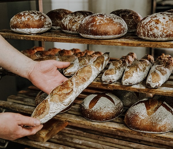 Bäcker nimmt frische Baguettes vom Backwagen